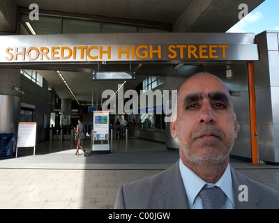 Ein asiatischer Mann posiert vor dem Eingang der S-Bahn Station Shoreditch High Street, East End, London England UK KATHY DEWITT Stockfoto