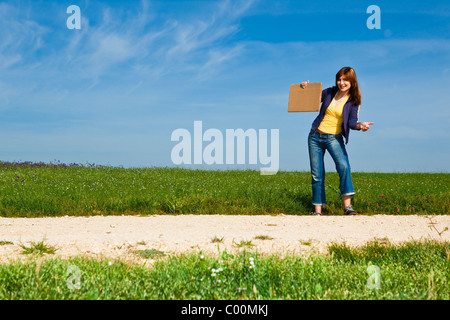 Junge Frau Trampen auf einer schönen grünen Wiese Stockfoto