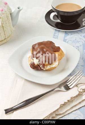 Afternoon Tea mit Schokolade bedeckt Choux Pastry Brötchen. Stockfoto