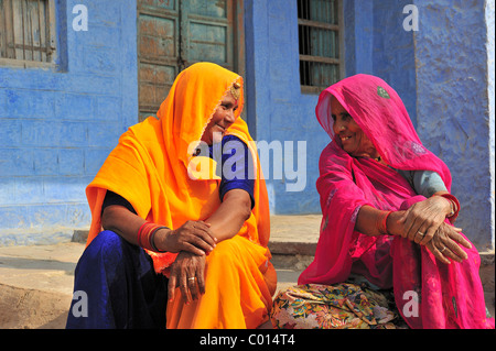 Zwei lächelnde indische Frauen tragen hell farbigen Saris sprechen außerhalb ihres Hauses, Rajasthan, Indien, Asien Stockfoto