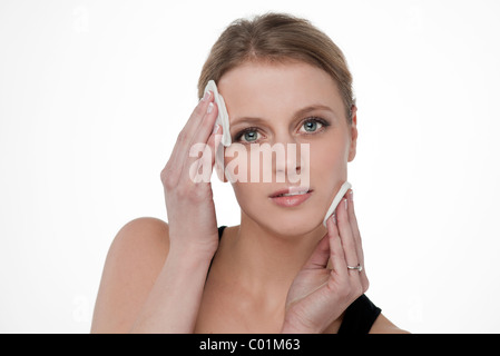 Blonde Frau machen sich mit Wattepads entfernen Stockfoto