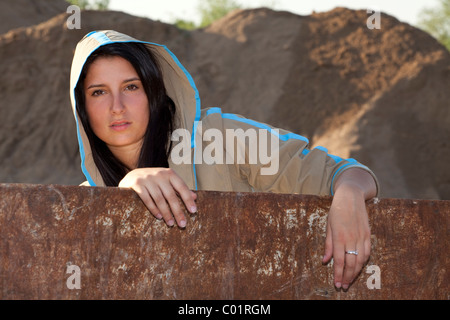 Junge Frau an einem rostigen Container gelehnt Stockfoto