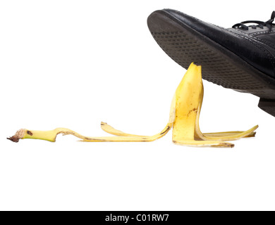 ein mans schwarzen Schuh fast zu betreten eine Bananenschale auf dem weißen Hintergrund isoliert Stockfoto