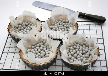 Leere Gebäck Fällen auf einem kühlenden Tablett mit Backen Bohnen nach Blind gebacken Stockfoto