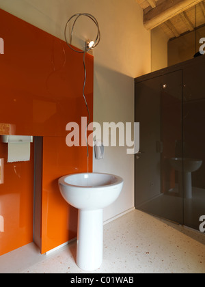 elegante und moderne Badezimmer mit orange Wand und weißer Keramik Waschbecken in Spalte Stockfoto