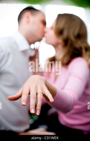 Zarte Frauenhand mit einem Verlobungsring, küssen paar hinten Stockfoto