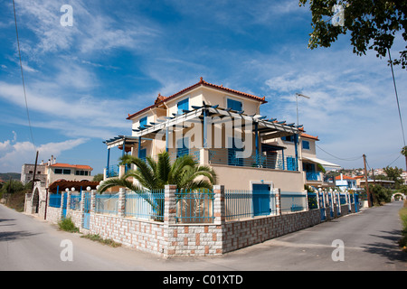 Griechisches Dorf mit traditionellen blauen Vorhängen und Palme im Garten Stockfoto