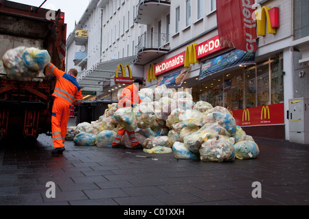 Müllsäcke mit Abfallverpackungen stapelten sich auf der Straße Werden von außerhalb eines McDonald's Fast-Food-Restaurants weggebracht Müllsammler / Müllmänner Stockfoto