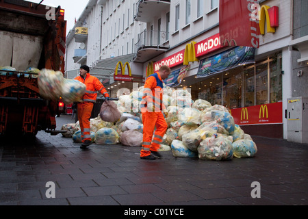 Müllsäcke mit Abfallverpackungen stapelten sich auf der Straße Werden von außerhalb eines McDonald's Fast-Food-Restaurants weggebracht Müllsammler / Müllmänner Stockfoto