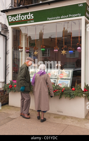 Ein älteres Ehepaar auf der Suche in einem Immobilienmakler Fenster in Aldeburgh, Suffolk, England, Großbritannien, Uk Stockfoto