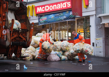 Müllsäcke mit Abfallverpackungen stapelten sich auf der Straße Werden von außerhalb eines McDonald's Fast-Food-Restaurants weggebracht Müllsammler / Müllmänner Stockfoto