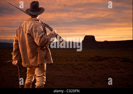 Cowboy mit Pistole steht Blick auf Sonnenuntergang in Monument Valley in Utah. Stockfoto