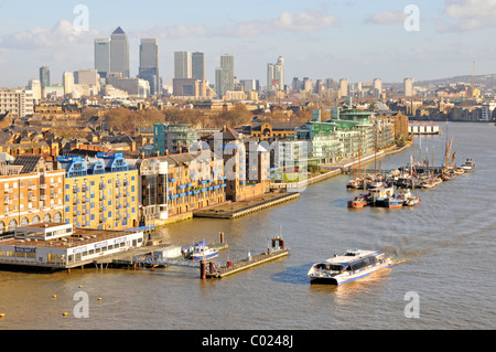 Wasserbus mit Thames Clipper in Tower Hamlets Stadtlandschaft & Pool von London mit Apartmentblöcken am Flussufer und Skyline von Canary Wharf jenseits von England Stockfoto