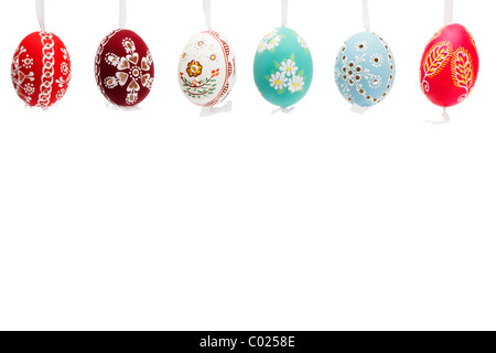 hängende Reihe von Hand bemalte Ostereier auf weißem Hintergrund Stockfoto