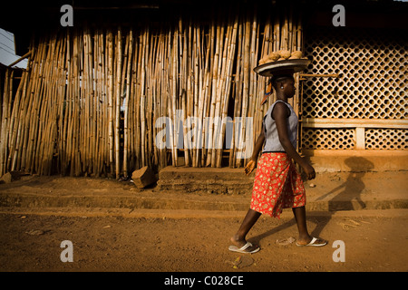 Eine Mädchen trägt Kokosnüsse geht auf eine Straße in Makeni, Sierra Leone auf Mittwoch, 25. Februar 2009. Stockfoto