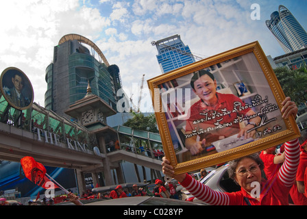 Red Shirt Demonstranten halten Zeichen des gestürzten Premierminister Thaksin vor Central World, rotes Hemd Protest durch einen Brand zerstört. Stockfoto