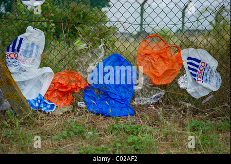 Kunststoff Tragetaschen aus verschiedenen Geschäften gegen Kettenglied Fechten bei sehr starkem Wind geblasen einkaufen. Stockfoto