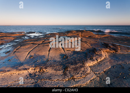 Felsformationen gefangen bei schwachem Licht der Sonne gegen Bay in North Yorkshire. Stockfoto