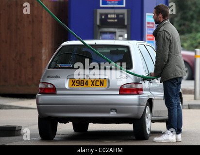 MENSCHEN, DIE AUTOS AN TANKSTELLE TANKEN Stockfoto