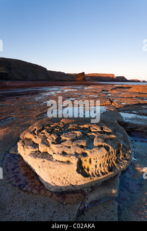 Felsformationen gefangen bei schwachem Licht der Sonne gegen Bay in North Yorkshire. Stockfoto