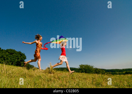 Frau und Mädchen laufen mit einem Drachen auf einer Wiese im Schwarzwald, Baden-Wuerttemburg, Deutschland, Europa Stockfoto