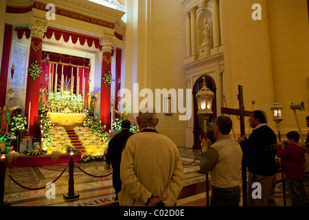 Menschen beten im Grab oder im Tabernakel der Pfarrkirche in eine benutzerdefinierte gehaltenen ganz Malta am Vorabend des Karfreitags. Stockfoto