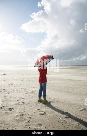 Frau mit Sonnenschirm am Strand, Wind, Donner cloud, Langeoog Insel, Ostfriesischen Inseln, Nordsee, Deutschland, Europa Stockfoto