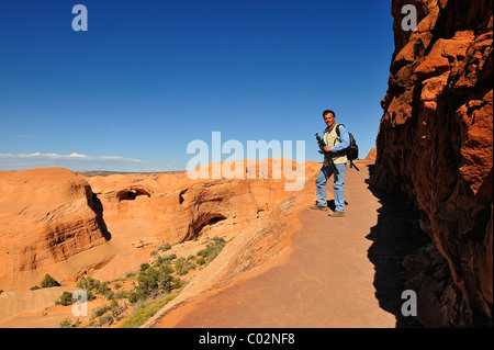 Mann-Fotograf zu Fuß auf dem Weg zum Delicate Arch im Arches National Park in Utah, in der Nähe von Moab, USA Stockfoto