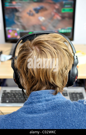 Junger Mann einen Kopfhörer tragen, während auf einem Computer spielen Stockfoto