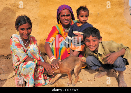 Eine indische Frau mit drei Kindern auf dem Boden saßen und hält einen kleinen Hund, Thar-Wüste, Rajasthan, Indien, Asien Stockfoto