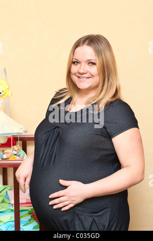 Schwangere junge Frau kaukasischen Stand in der Nähe des Babys Bett. Russischen Volkes Stockfoto