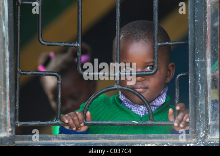 Junge, 4-5 Jahre, Blick durch vergitterten Fenstern, afrikanischen Kindes, Portrait, Tansania, Afrika Stockfoto