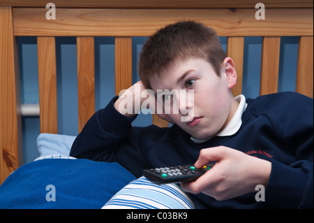 Ein MODEL Release Bild eines elf Jahre alten Jungen vor dem Fernseher in seinem Schlafzimmer im Vereinigten Königreich Stockfoto