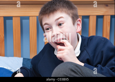 Ein MODEL Release Bild eines elfjährigen Jungen Kommissionierung seinen wackeligen Zahn in seinem Schlafzimmer im Vereinigten Königreich Stockfoto