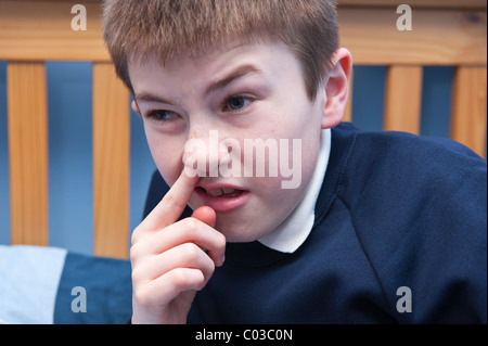 Ein MODEL Release Bild eines elfjährigen Jungen sammeln seine Nase in seinem Schlafzimmer im Vereinigten Königreich Stockfoto