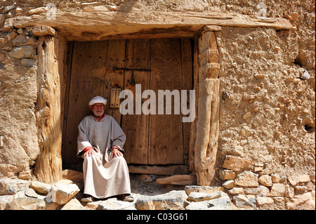 Älterer Berber Mann trägt einen traditionellen Nonnen und Turban sitzen am Eingang zu einem alten Lagersilo Ait Bouguemez Stockfoto