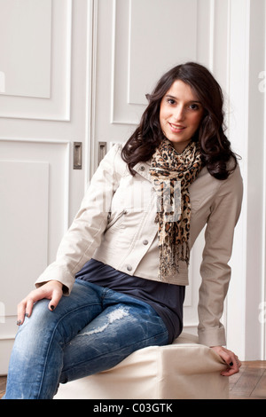 Junge Frau sitzt auf einem Hocker Stockfoto