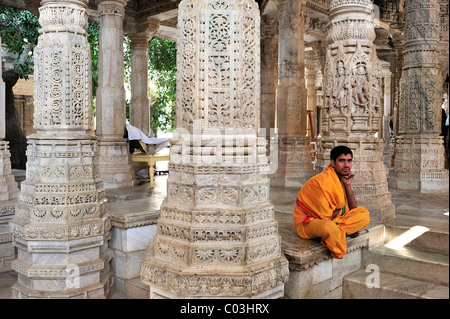 Junger Mönch tragen die traditionellen gelben Kutte in den Flur mit reich verzierten Marmorsäulen in den Tempel von Ranakpur Stockfoto