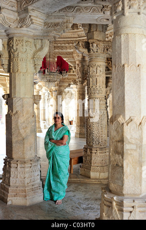 Indische Frau trägt einen traditionellen Sari in der inneren Halle mit reich verzierten Marmorsäulen in den Tempel von Ranakpur Stockfoto