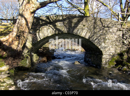 Eine kleine Steinbrücke überspannt ein Bach in den Fluss Greta, Threlkeld, Cumbria im englischen Lake District. Stockfoto