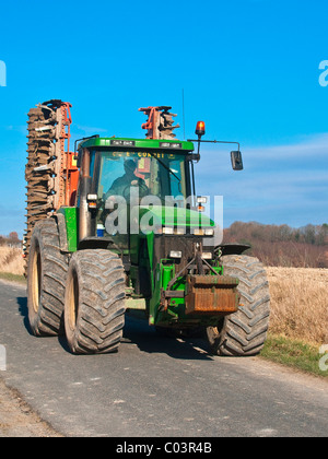 John Deere 8300 Traktor mit Disc-Roller auf Landstraße - Frankreich. Stockfoto