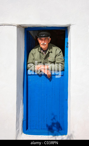 Ein Alter griechischer Mann lächelnd von der Tür seines Hauses in Ano Mera Dorf, Folegandros Insel, Kykladen, Griechenland Stockfoto