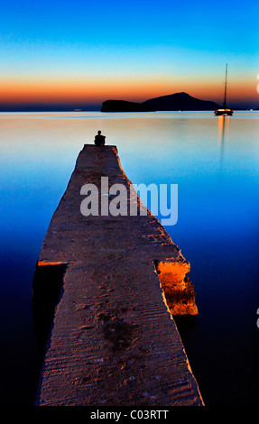 Ein einsamer Mann genießen den Sonnenuntergang am Strand in Sounion, sehr nahe an den alten Tempel von Poseidon, Attika, Griechenland. Stockfoto