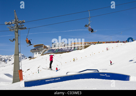 St. Anton am Arlberg, Tirol, Österreich, Europa. Stanton Park Funpark im Skigebiet Rendl mit Skifahrer auf Sprünge unter Sessellift Stockfoto