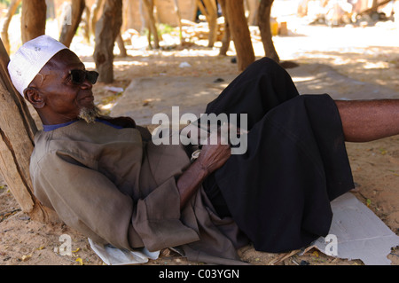 Senior muslimischen Mann mit gebrochenen Sonnenbrille ruhen im Schatten in der Dogon-Dorf Yendouma. Mali. Stockfoto
