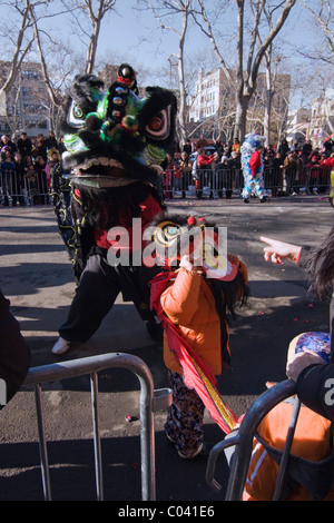 Young Boy in Lion Tanz Kostüm bekommt Ratschläge von seiner Mutter, während mit einem schwarzen Löwen in NYC Chinesische Neujahrsparade tanzen Stockfoto