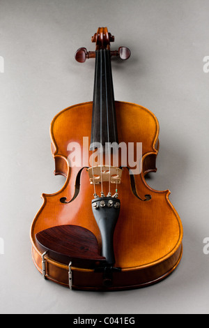 Klassische Violine oder eine Geige auf grauem Hintergrund isoliert, wie von der Vorderseite des Instruments zu sehen. Stockfoto