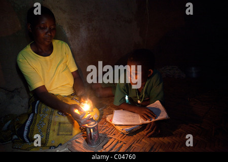 Eine Mutter leuchtet eine kleine Lampe für ihr Kind, indem in Masaka, Uganda, Ostafrika zu studieren. Stockfoto