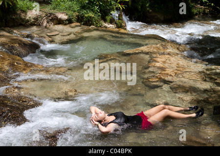 Junge Frau touristischen entspannt in einem flachen Wasserbecken an die Dunns River Falls in Jamaika. Stockfoto