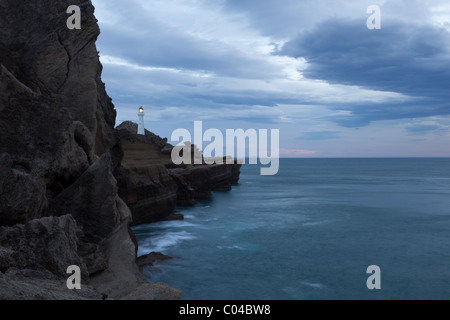 Castlepoint Leuchtturm mit seiner Lampe auf Neuseeland. Die Aufnahme wurde in der Morgendämmerung mit stürmischen Wolken im Hintergrund. Stockfoto